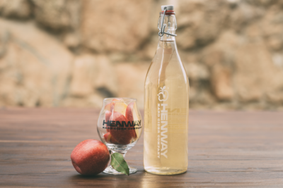 Henway Hard Cider growler displayed with a logo glass filled with Great Country Farms Apples
