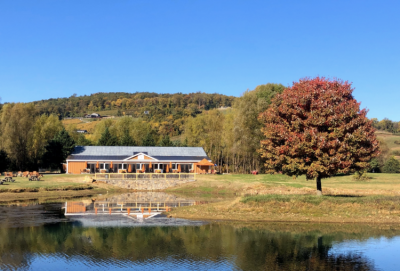 Henway Hard Cider's new building located by the pond at Great Country Farms in the foreground and the Blue Ridge Mountains in the background in this Northern Virginia Hard Cider Tasting Room in Bluemont, Virginia.