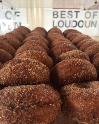 Cider Donuts stacked in the foreground with Great Country Farms Best of Loudoun Award Banner in the background in our Northern Virginia Bakery and Coffee shop.