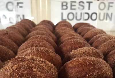 Cider Donuts stacked in the foreground with Great Country Farms Best of Loudoun Award Banner in the background