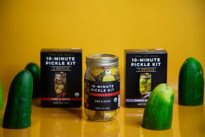 Pickling perfection cucumber on a fork with Johnny and Pearl pickling spice boxes