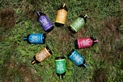 All the flavors of Mad Magic Ginger Lemon Kombucha displayed on a circle in the grass in the farm Market at Great Country Farms