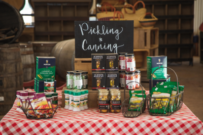 Pickling perfection cucumber on a fork with Johnny and Pearl pickling spice boxes and jars on display in the Farm Market at Great Country Farms