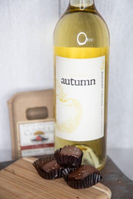A bottle of Bluemont Vineyard's Farm Table Red Wine is displayed with Farmhouse Sea Salt Carmel Chocolates in the Market at Great Country Farms
